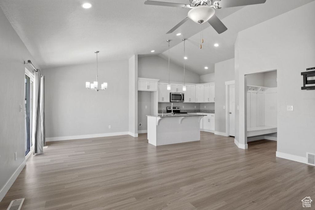 Kitchen featuring stainless steel appliances, baseboards, open floor plan, white cabinetry, and recessed lighting
