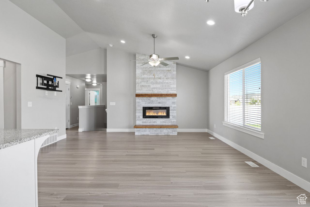 Unfurnished living room featuring a stone fireplace, ceiling fan, light wood-style flooring, baseboards, and recessed lighting