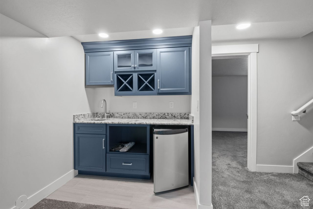 Indoor wet bar featuring fridge, baseboards, stairs, and recessed lighting