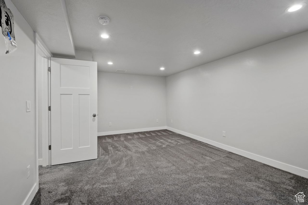 Below grade area featuring dark carpet, recessed lighting, and baseboards