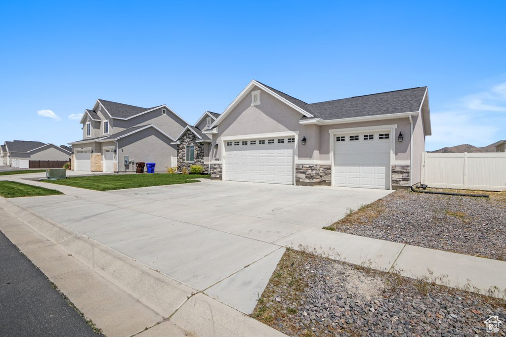 Craftsman house featuring a garage, stone siding, concrete driveway, and stucco siding
