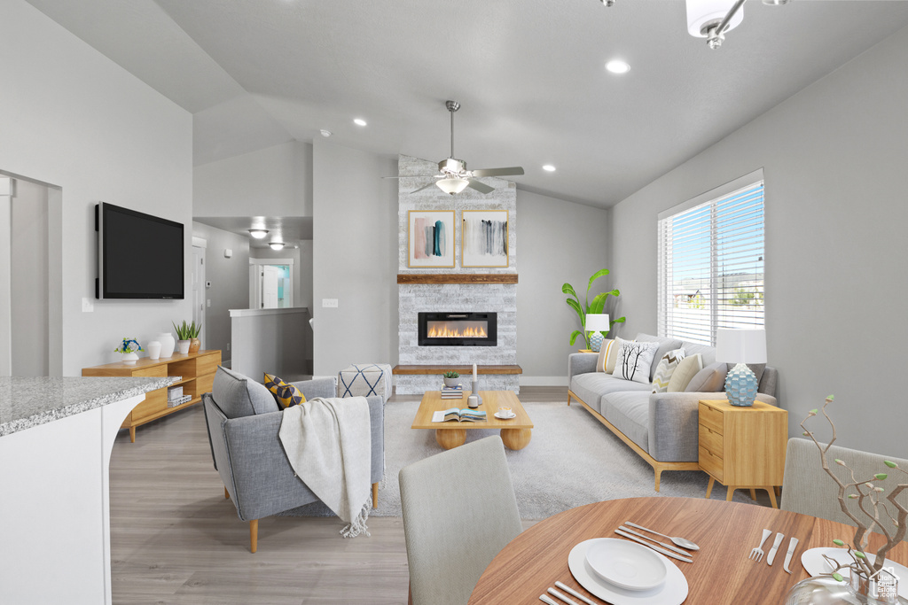 Living room featuring light wood-style floors, lofted ceiling, a fireplace, recessed lighting, and ceiling fan
