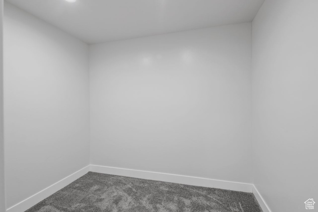 Spare room featuring dark colored carpet and baseboards
