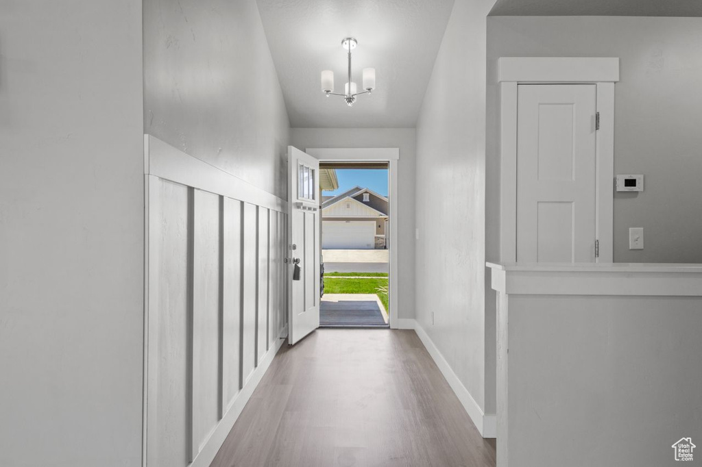 Entryway featuring wood finished floors, a chandelier, and baseboards