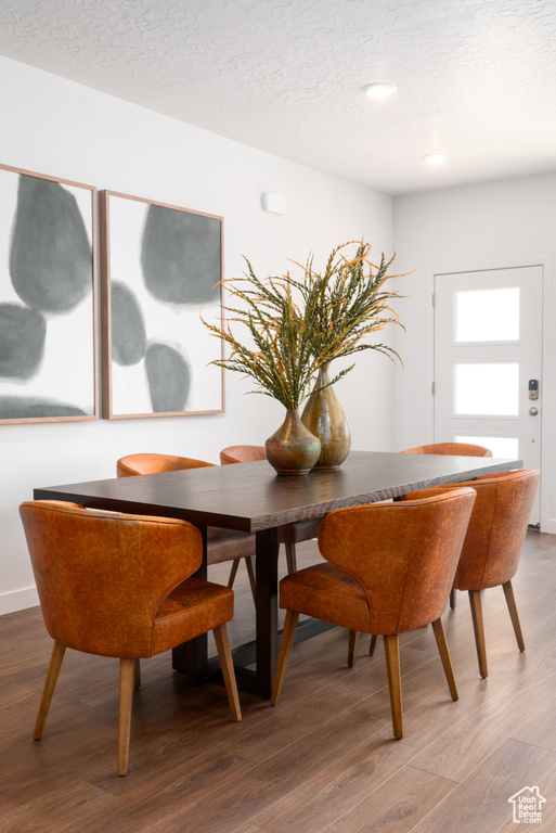 Dining space with a textured ceiling, wood finished floors, and recessed lighting