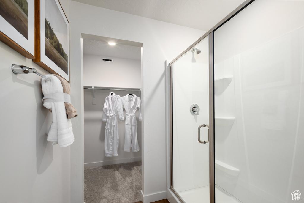 Bathroom with a shower stall and a walk in closet