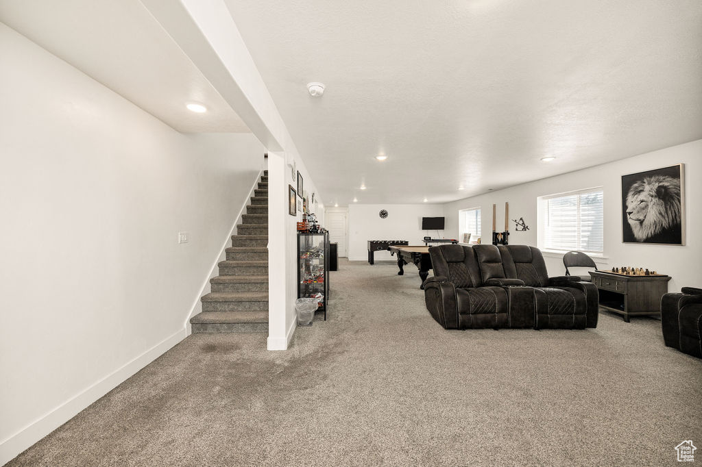 Carpeted living room featuring stairway, baseboards, and recessed lighting
