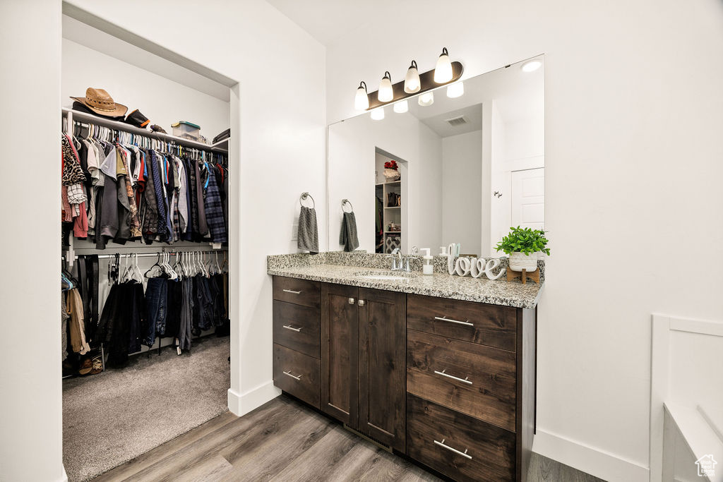 Full bathroom featuring vanity, wood finished floors, a spacious closet, and baseboards