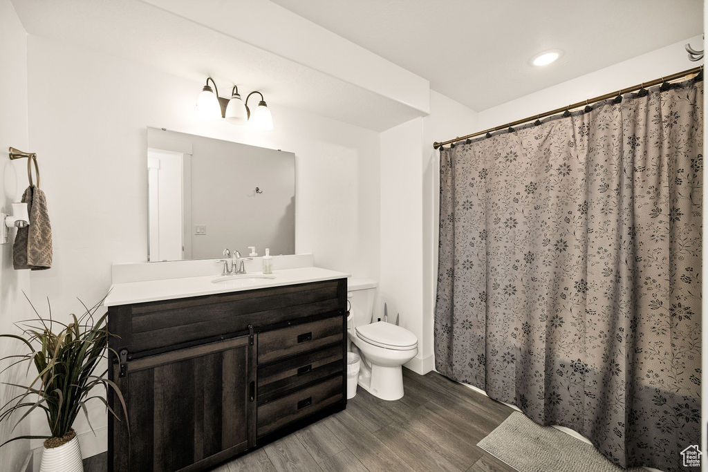Full bathroom featuring wood finished floors, toilet, vanity, recessed lighting, and a shower with curtain