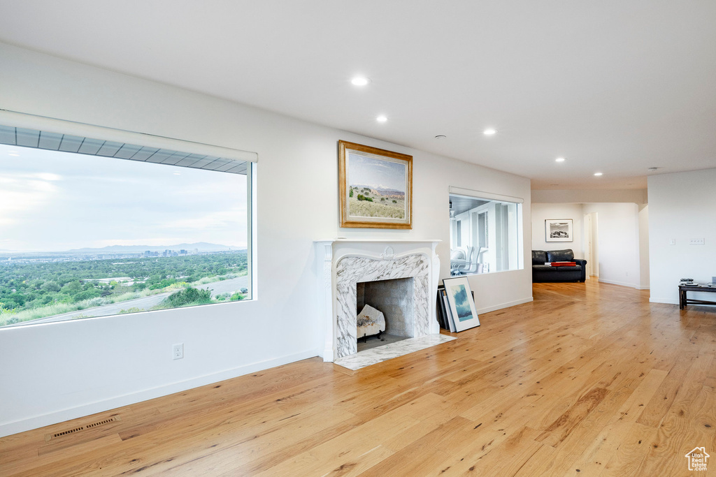 Unfurnished living room featuring recessed lighting, a premium fireplace, wood finished floors, and baseboards