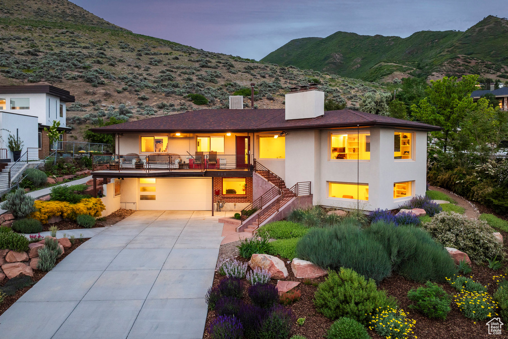 View of front of house featuring stairway, stucco siding, a chimney, a mountain view, and driveway