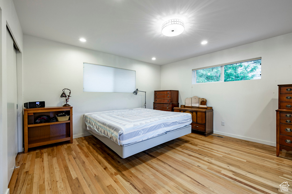 Bedroom featuring light wood-type flooring, baseboards, recessed lighting, and a closet