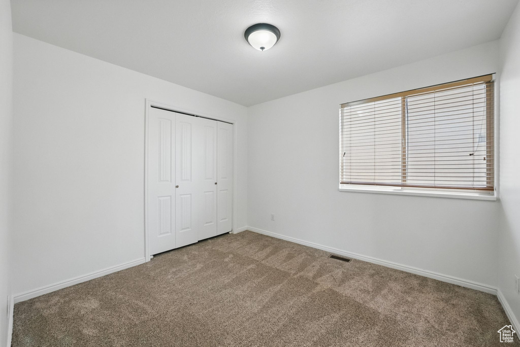 Unfurnished bedroom featuring carpet, baseboards, and a closet