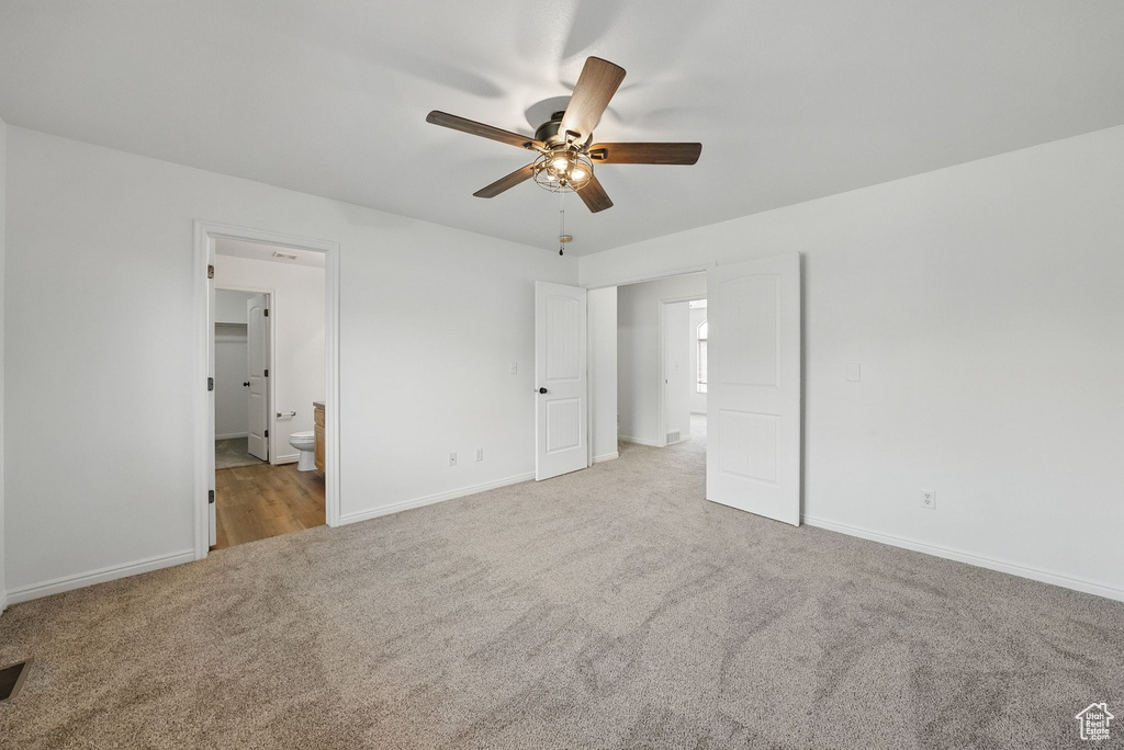 Unfurnished bedroom featuring carpet floors, baseboards, ensuite bath, and a ceiling fan