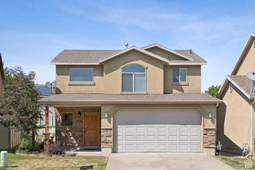 View of front of home featuring concrete driveway, stone siding, an attached garage, and stucco siding