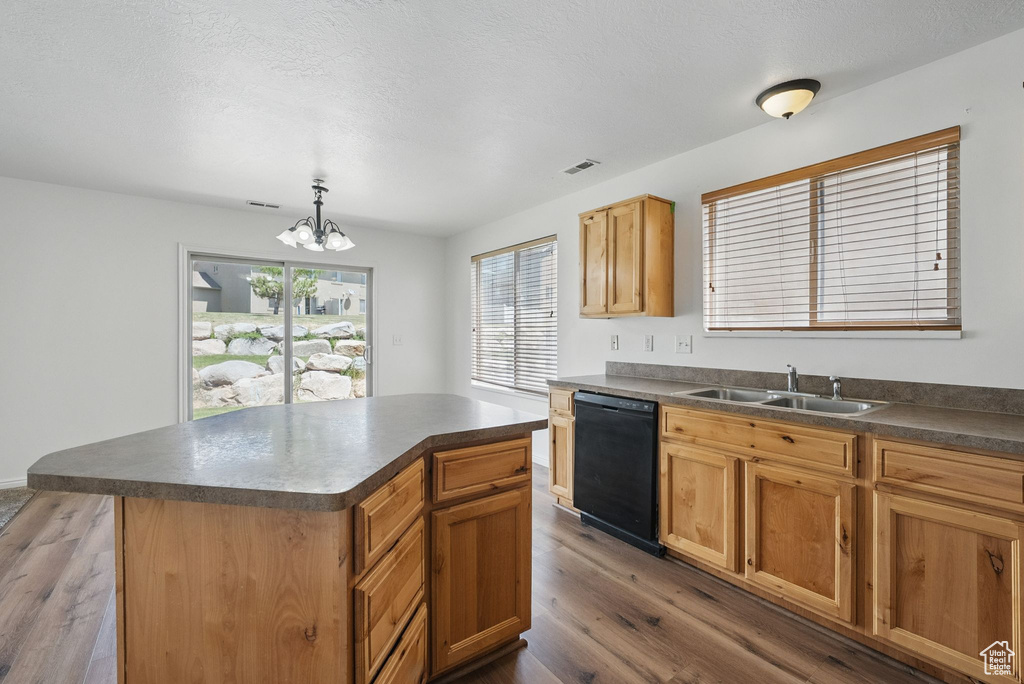 Kitchen featuring black dishwasher, a sink, dark countertops, and dark wood-style flooring