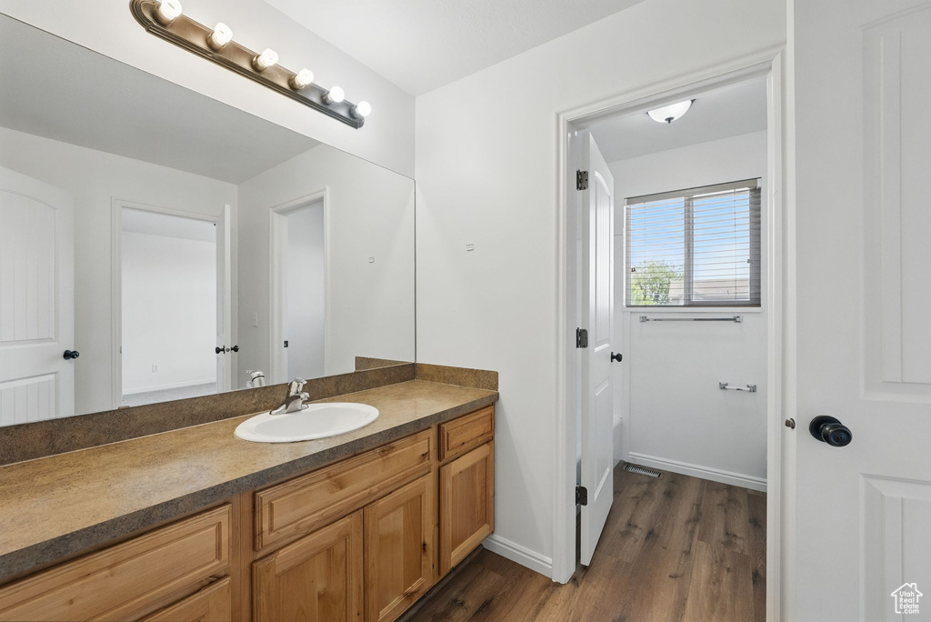 Bathroom with vanity, wood finished floors, and baseboards