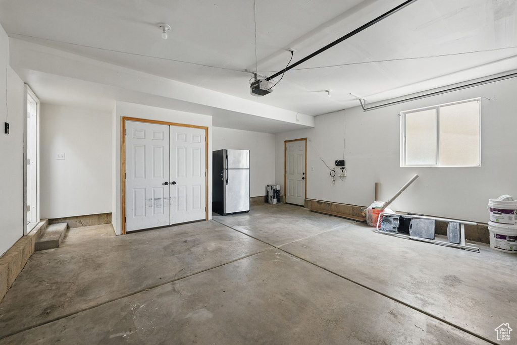 Garage with freestanding refrigerator and a garage door opener