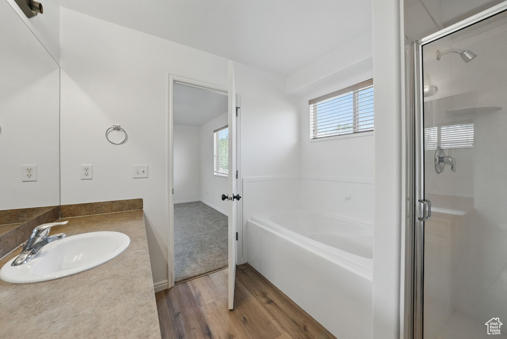 Bathroom with wood finished floors, a bath, a stall shower, and vanity