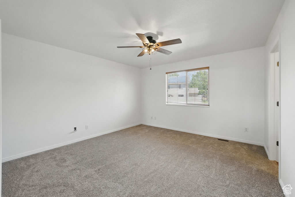 Carpeted spare room with a ceiling fan and baseboards