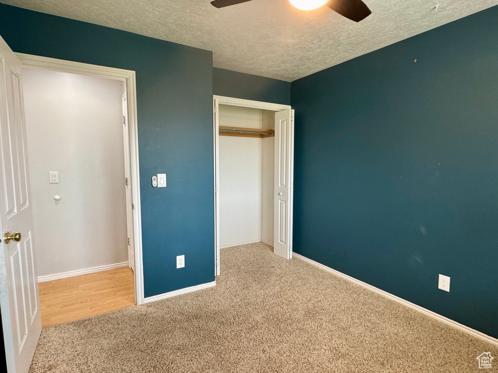 Unfurnished bedroom featuring carpet flooring, a textured ceiling, baseboards, a closet, and ceiling fan