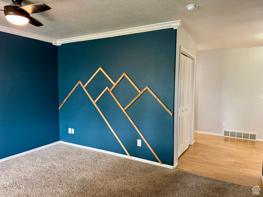 Carpeted empty room featuring crown molding, a ceiling fan, a smoke detector, baseboards, and a textured ceiling