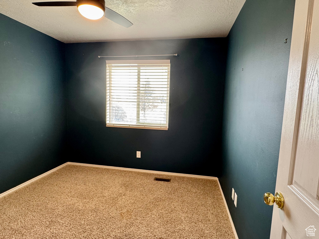 Carpeted spare room with a ceiling fan, a textured ceiling, and baseboards