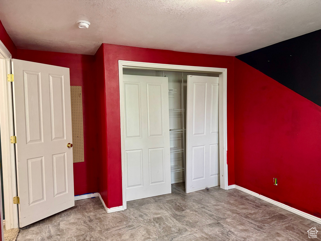Unfurnished bedroom with baseboards, a closet, and a textured ceiling