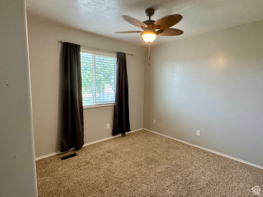 Carpeted spare room featuring a ceiling fan and baseboards
