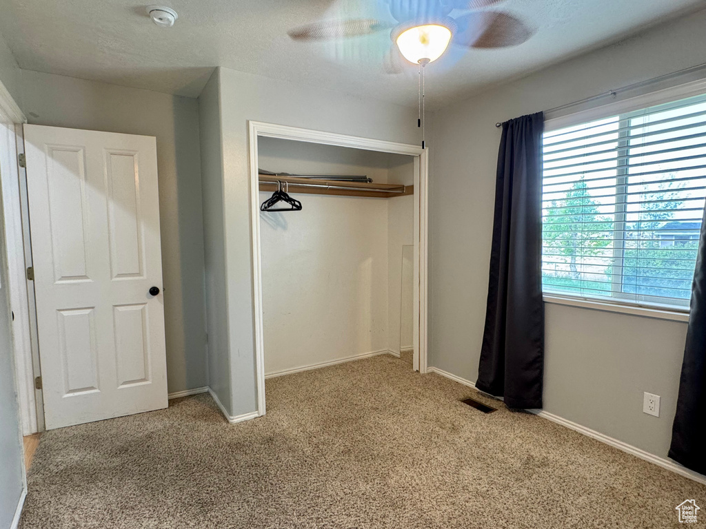 Unfurnished bedroom with carpet flooring, a closet, baseboards, and ceiling fan