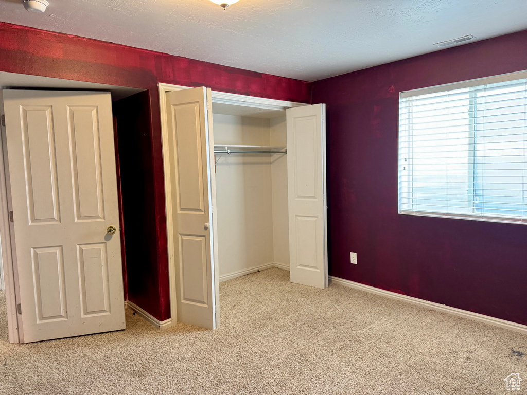 Unfurnished bedroom featuring carpet, a closet, and baseboards