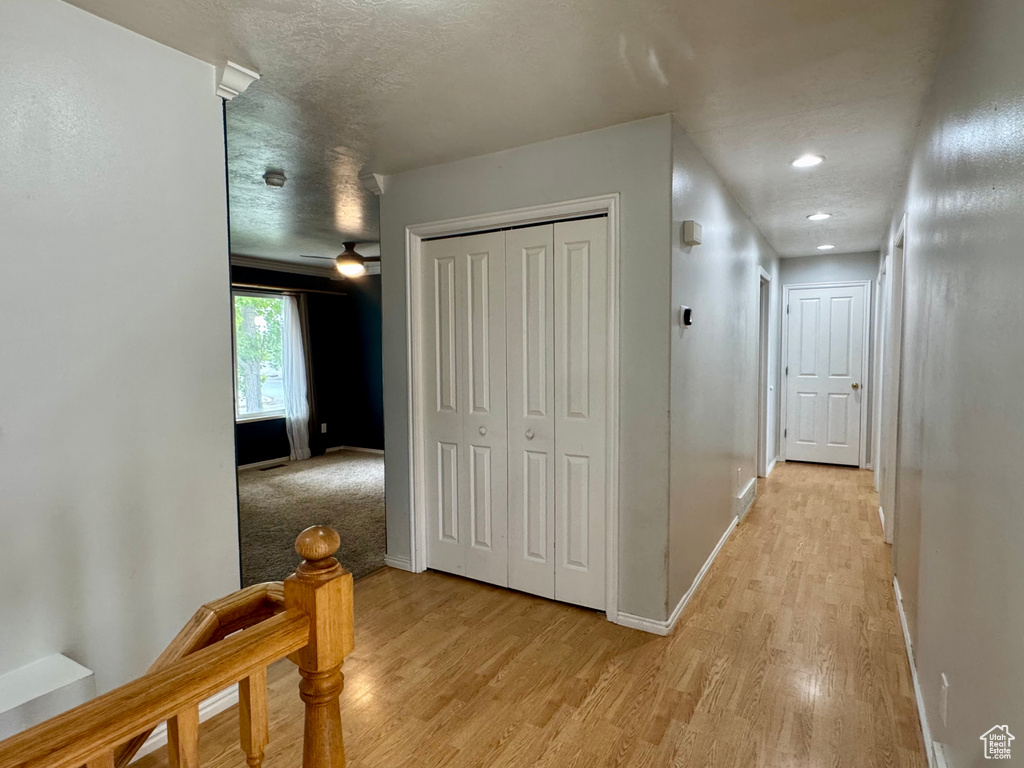 Hall with light wood-style flooring, baseboards, a textured ceiling, and recessed lighting