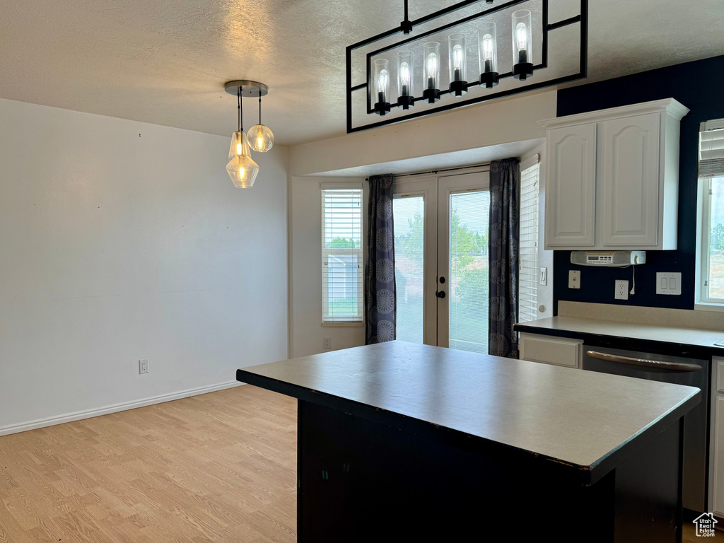 Kitchen featuring french doors, healthy amount of natural light, light wood finished floors, white cabinetry, and a textured ceiling