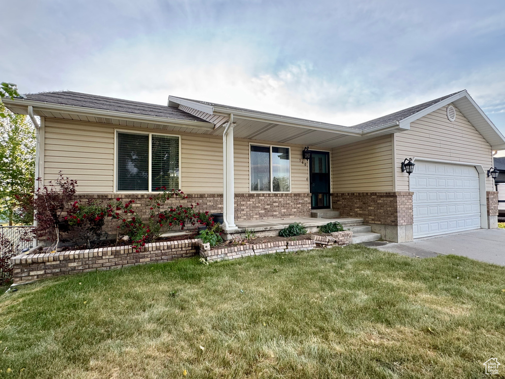 Ranch-style house with brick siding, a garage, concrete driveway, a front yard, and roof with shingles
