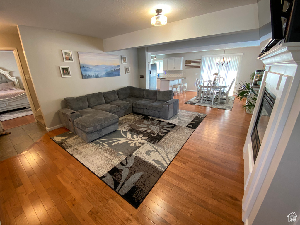 Living room with wood-type flooring, baseboards, a glass covered fireplace, and a chandelier