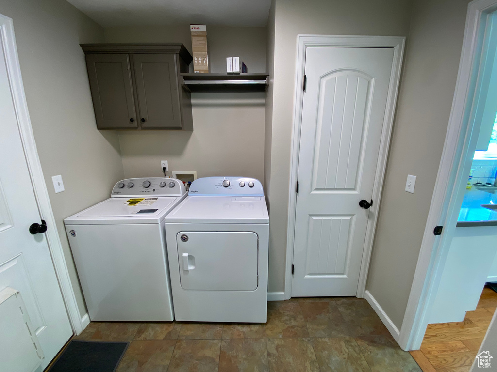 Laundry room with washing machine and dryer, cabinet space, baseboards, and stone finish floors