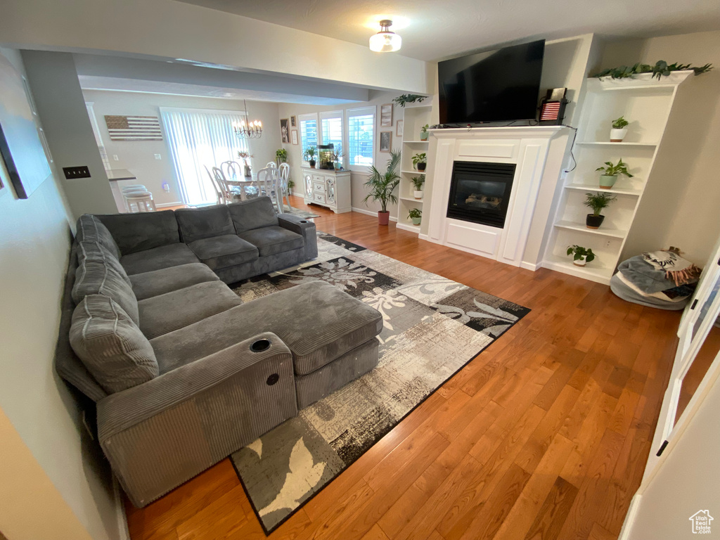 Living area featuring a chandelier, wood finished floors, and a glass covered fireplace