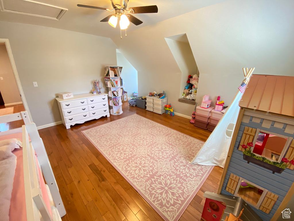 Bedroom featuring wood finished floors, lofted ceiling, ceiling fan, and baseboards