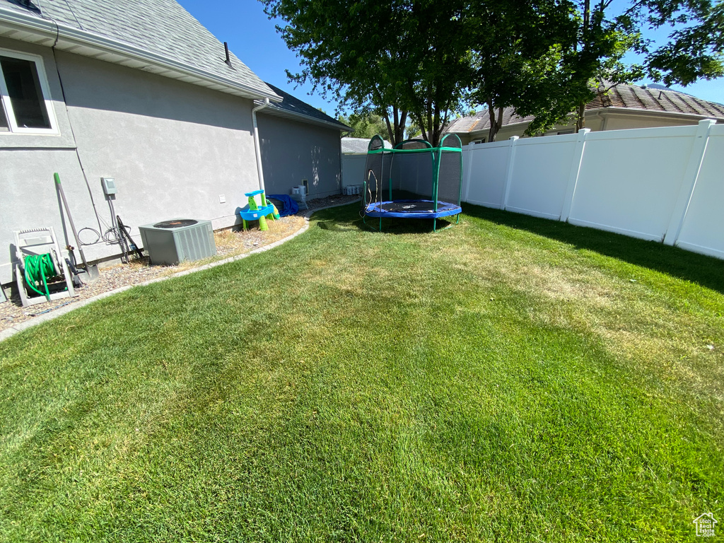 View of yard with a trampoline and cooling unit