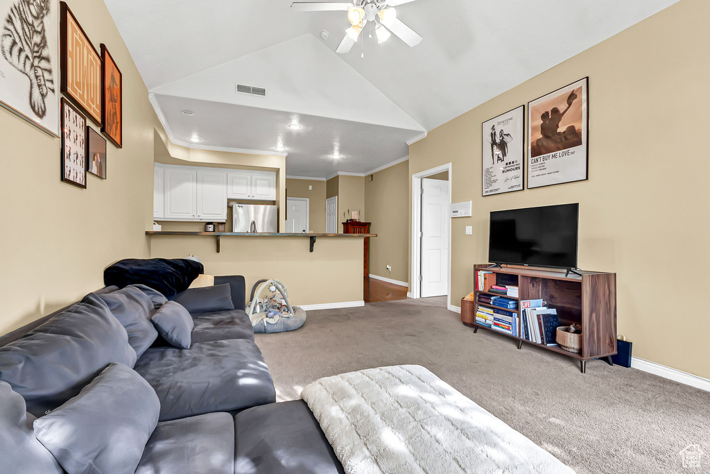 Living room with carpet flooring, a ceiling fan, lofted ceiling, and baseboards