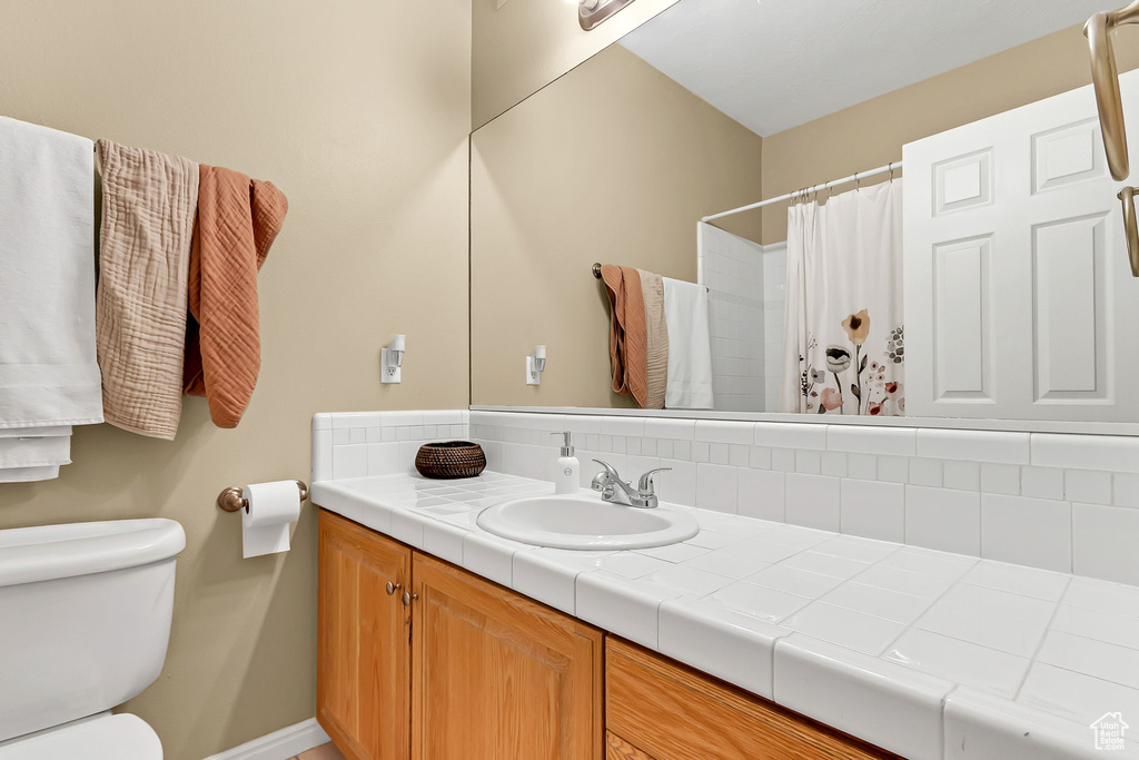 Full bath with toilet, vanity, baseboards, curtained shower, and backsplash