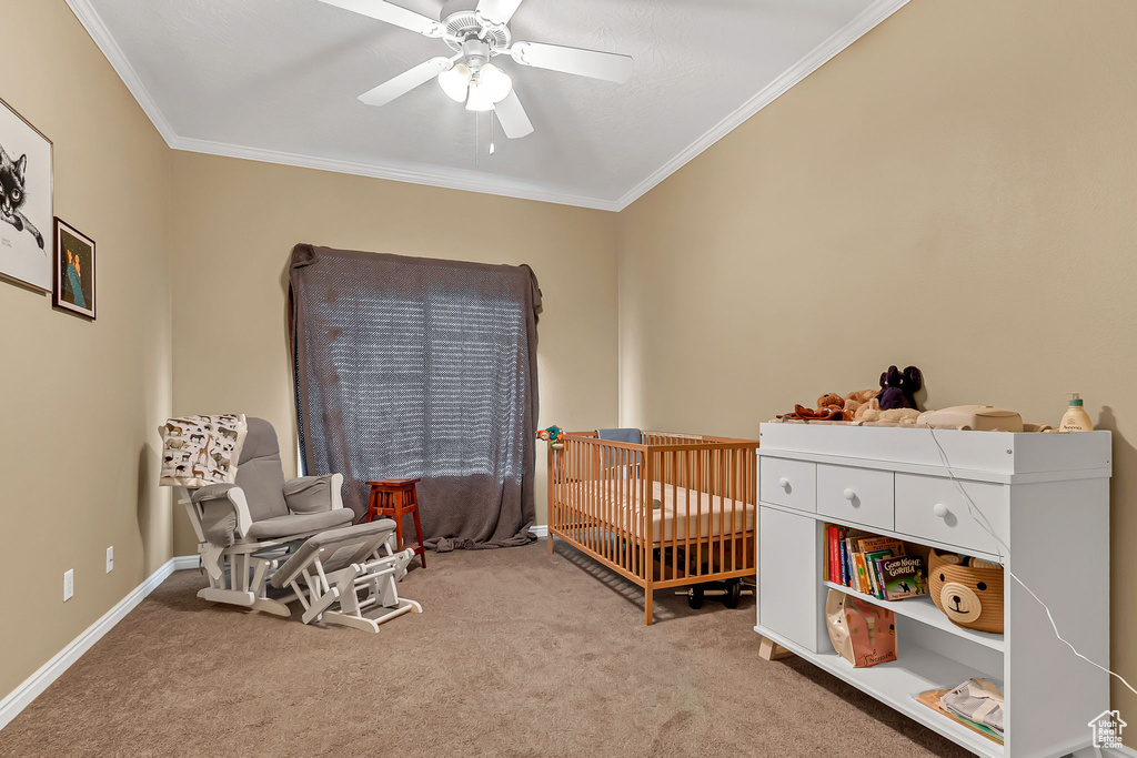 Bedroom with carpet, a crib, ornamental molding, ceiling fan, and baseboards