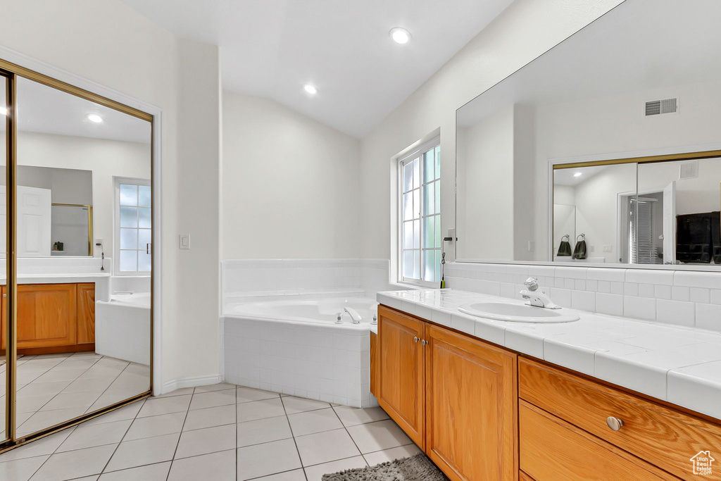 Bathroom featuring vanity, a bath, tile patterned floors, recessed lighting, and vaulted ceiling