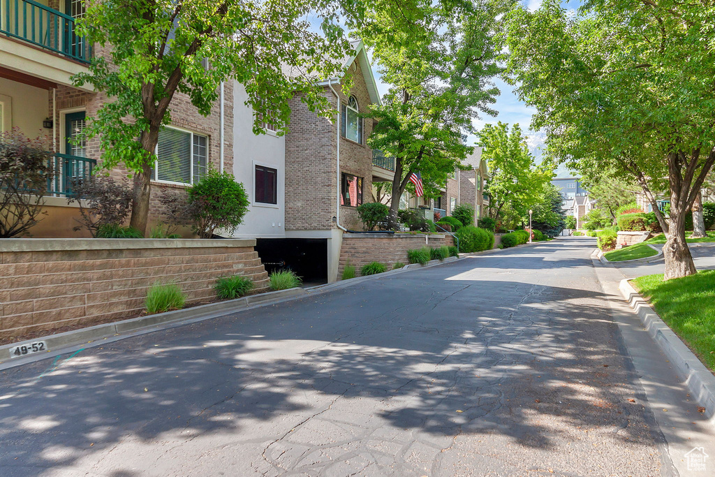 View of asphalt road featuring a residential view and curbs