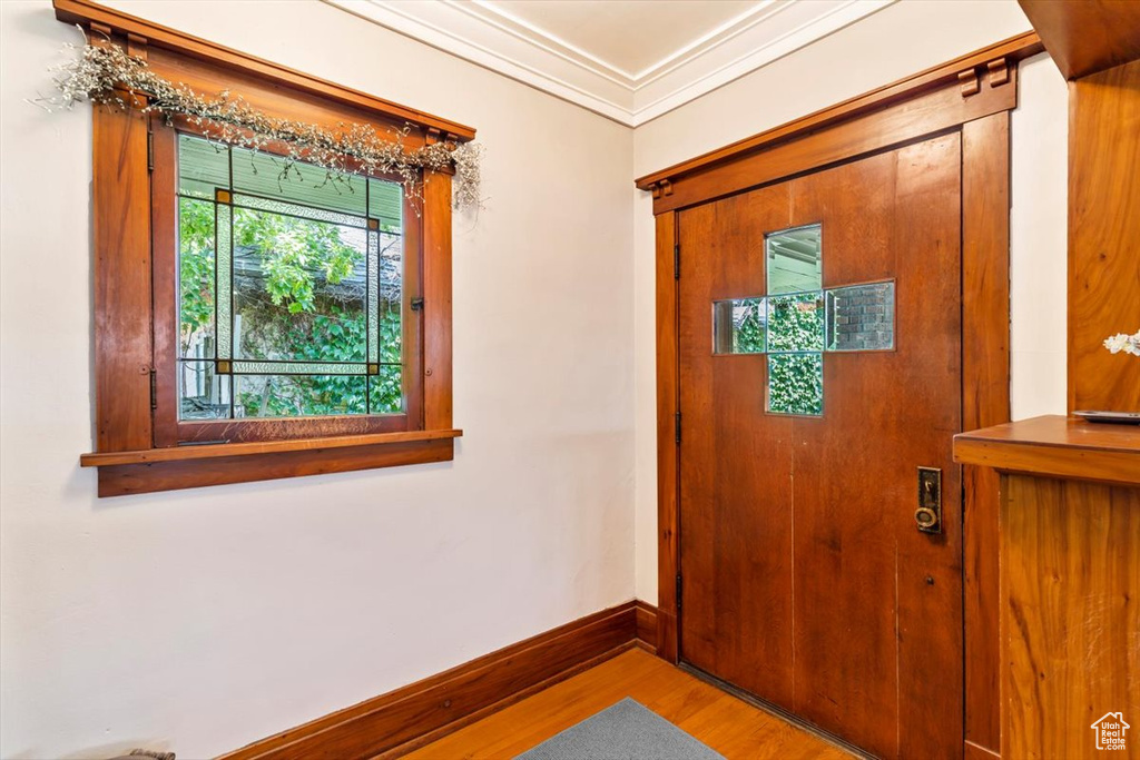 Foyer entrance with wood finished floors, baseboards, and ornamental molding
