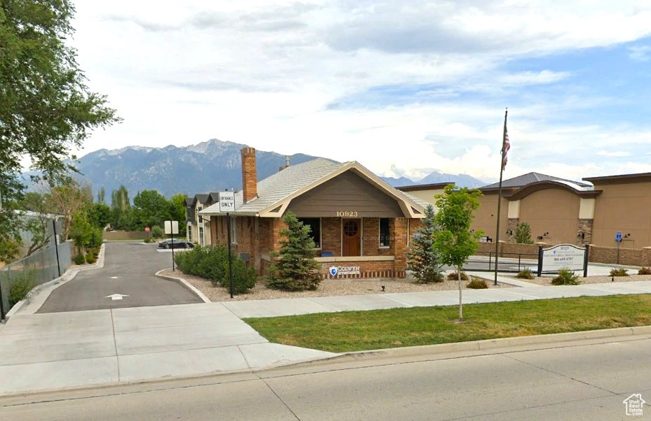 Ranch-style home with a mountain view, a chimney, brick siding, and driveway