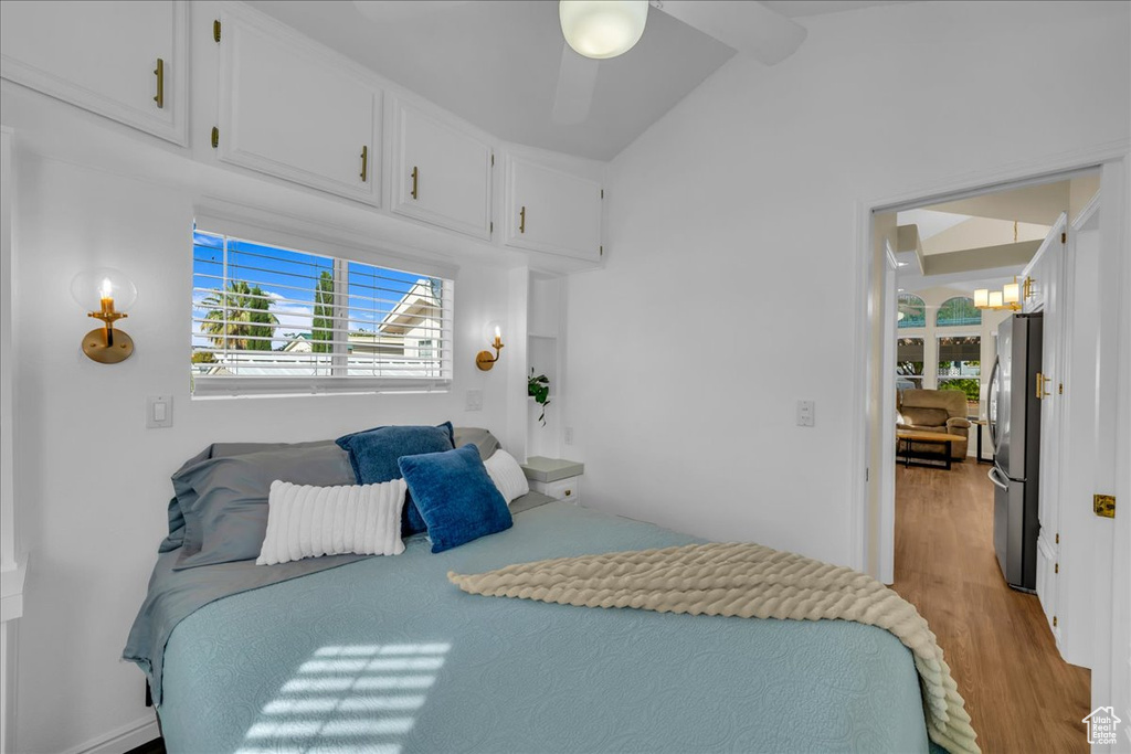 Bedroom with freestanding refrigerator, light wood-type flooring, lofted ceiling, and a chandelier