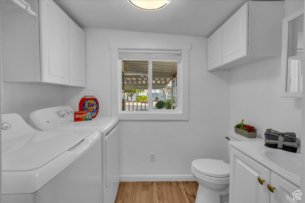 Laundry room with separate washer and dryer, light wood finished floors, and baseboards