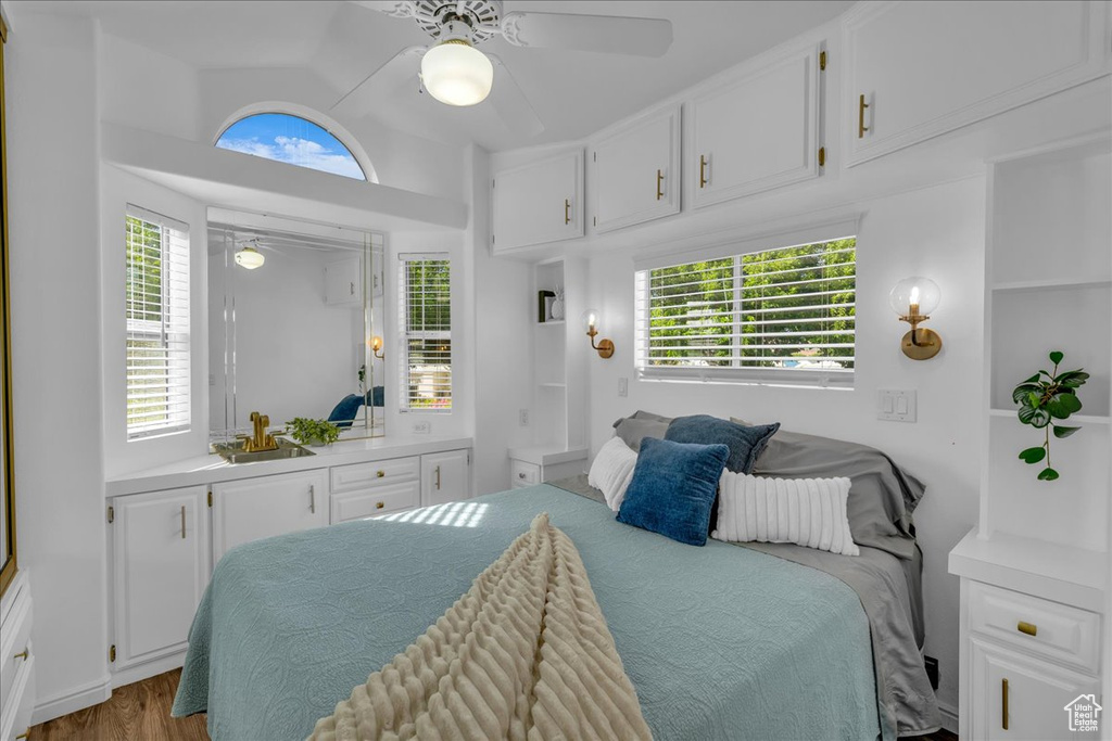 Bedroom featuring vaulted ceiling, multiple windows, wood finished floors, and ceiling fan
