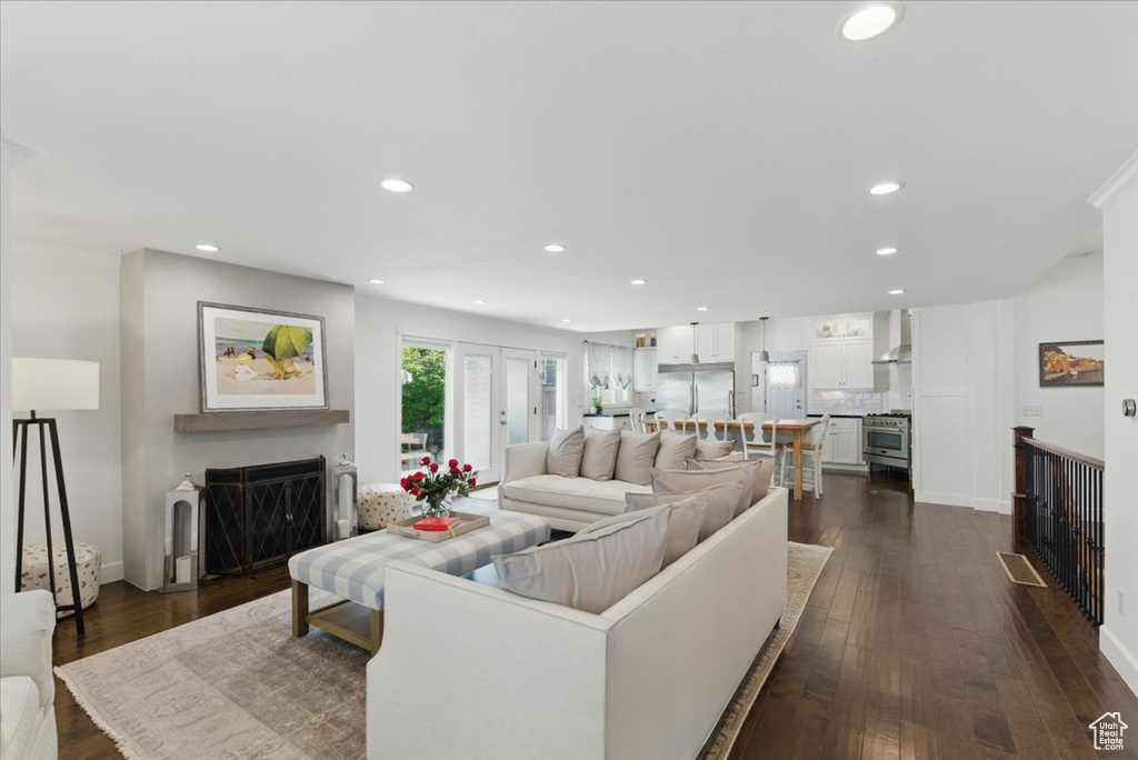 Living room featuring a fireplace, recessed lighting, dark wood-type flooring, and baseboards